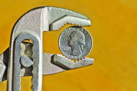 Close up of an Dollar Coin between pliers, concept of financial crisisの写真素材