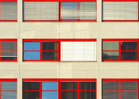 three lines of red windows in an office buildingの写真素材