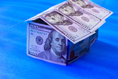 House shape made from 100 dollar bills over blue backgroundの写真素材
