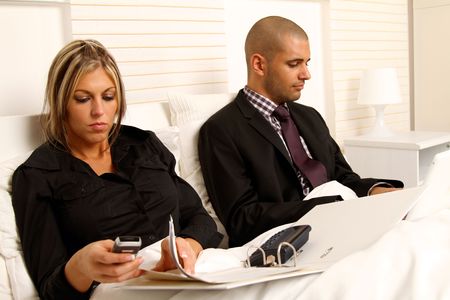 Workaholic couple in bedroomの写真素材