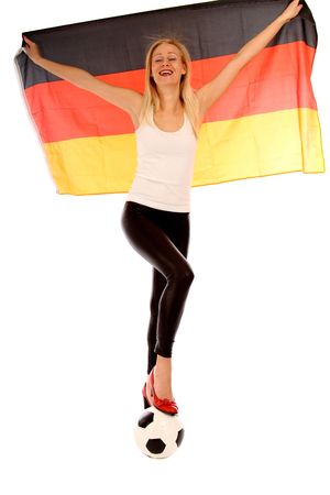 Blond woman holding up the german flag and stepping on a footballの写真素材