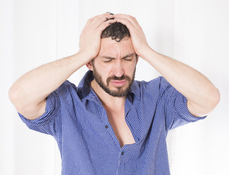 bearded man in blue shirt having a headacheの写真素材