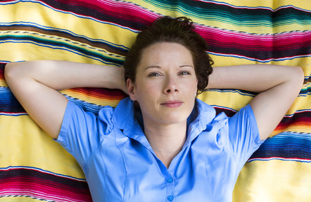 young woman is lying on a blanket on grass and smilesの写真素材