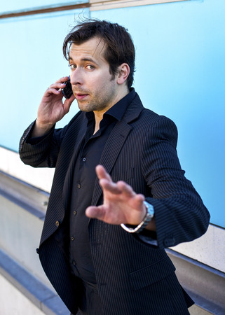 businessman on the phone giving a sign with his hand to be not interruptedの写真素材