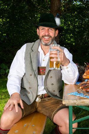 bavarian man sitting on bench with a beer mugの写真素材