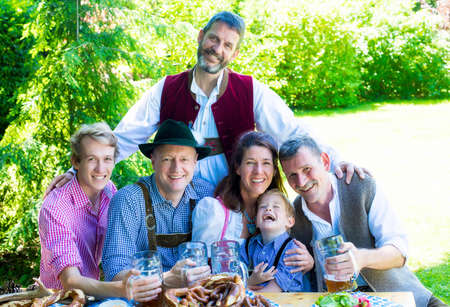 bavarian family sitting outside on a bench and drinking beerの写真素材