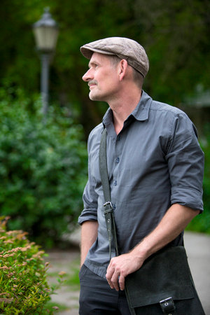 man standing in Park with cap and bag