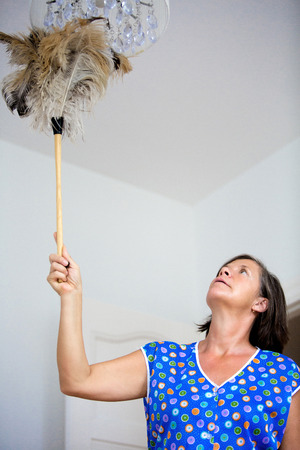 woman cleaning a lamp with feather dustersの写真素材