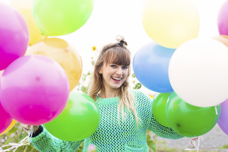 young woman with ballons on a field of flowersの写真素材