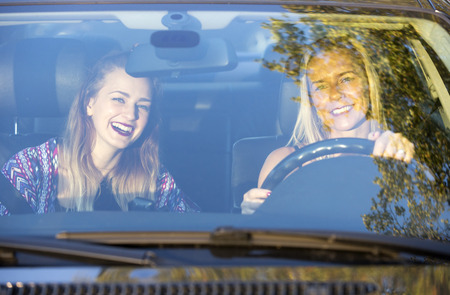 two women sitting in a car and laugh
