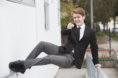 man in a suit jumping at a wall and pointing his fingerの写真素材