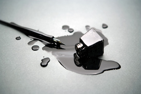 old fashioned pen with a glass of spilled black inkの写真素材