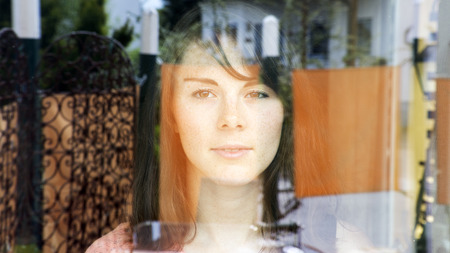 portrait of beautiful woman looking through window