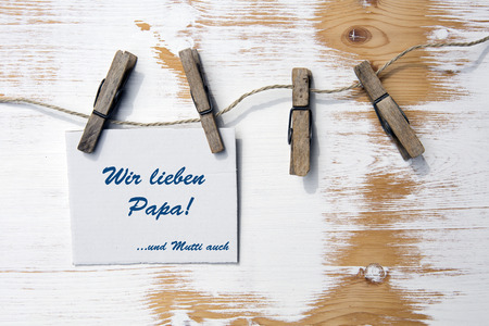 sign on a clothes line with german text:Wir lieben Papa...und Mutti auch (we love Dad and Mom too)の写真素材
