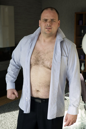 fat man with open shirt makes a fist and looks at cameraの写真素材
