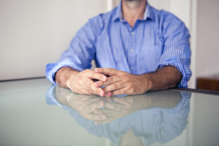 closeup of man's hands resting on tableの写真素材