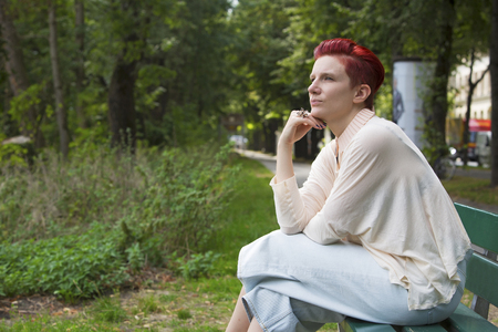 red-haired woman sitting on a bench in a park and relaxesの写真素材