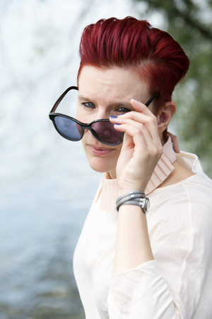 portrait of red-haired woman with sunglasses outdoorsの写真素材