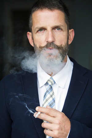 portrait of a handsome businessman smoking a cigaretteの写真素材