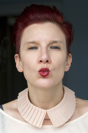 portrait of beautiful red-haired woman giving a kiss