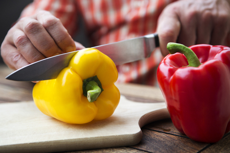close-up of man cutting peppers on wooden tableの写真素材