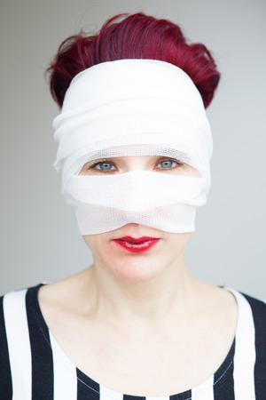 portrait of beautiful red haired woman with bandages wrapped around her headの写真素材