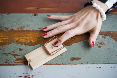 closeup of woman's finger with red nailpolish in mousetrap