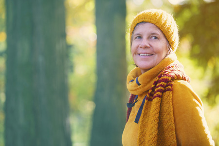 portrait of woman standing in front of trees in the fallの写真素材