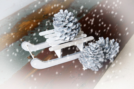 toy christmas sleigh with pinecones and snowflakes on wooden vintage board