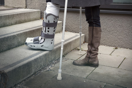 closeup of woman walking with a plaster cast and crutchesの写真素材