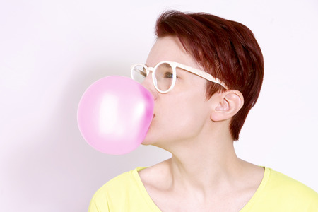 red-haired woman with white glasses and big bubble of chewing gum