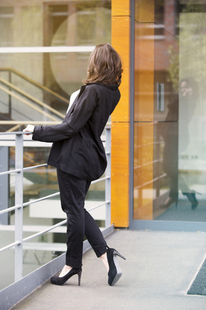 backside of young businesswoman standing outside and talking on phoneの写真素材