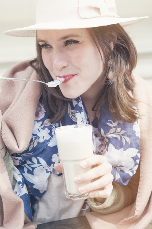 young woman sitting at Cafe with coffee wearing a hat and blanketの写真素材