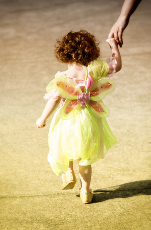 cute little girl in a fairy dress walking and holding mother's handの写真素材