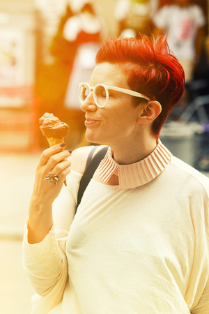 red-haried woman standing in the streets and eating chocolate icecreamの写真素材