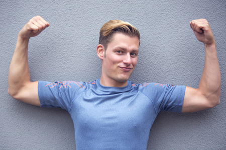 portrait of handsome blond young man showing off his muscles