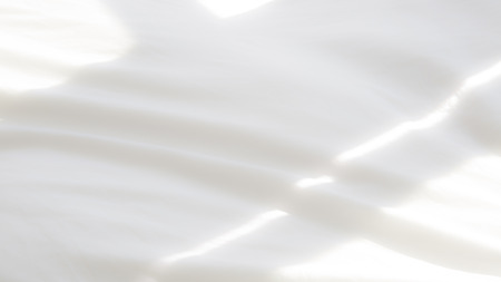 closeup of soft white bedsheets in the morning lightの写真素材