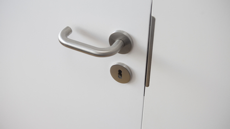 closeup of closed white door with silver handleの写真素材