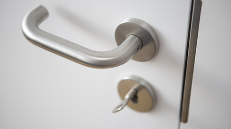 closeup of white door with silver door handle and keyの写真素材