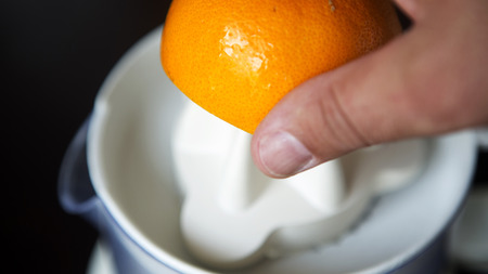 closeup of a hand squeezing an orange with a juicerの写真素材