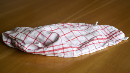 white red checkered wrinkled dishcloth on a wooden tableの写真素材