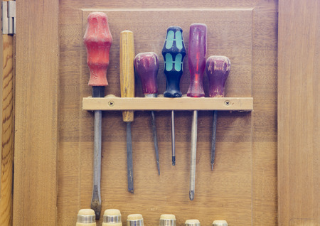 several screwdrivers hanging on wooden wall at workshop