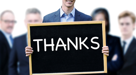 young businessman holding a sign with the word Thanks and group of people behind himの写真素材