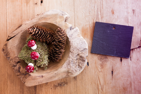 chalkboard and wooden bowl with pinecones and mushrooms on wooden tableの写真素材