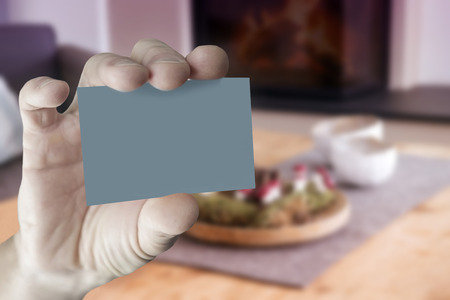 closeup of mans hand holding an empty business card in front of stylish living roomの写真素材
