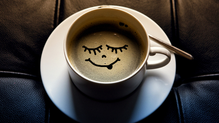 white coffee cup with funny face on black leatherの写真素材