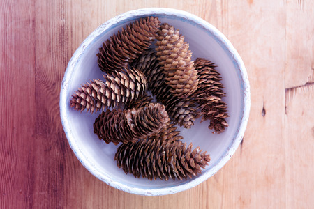 ceramic bowl with pinecones on wooden tableの写真素材