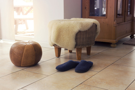 stool with fleece and slippers in living room by window
