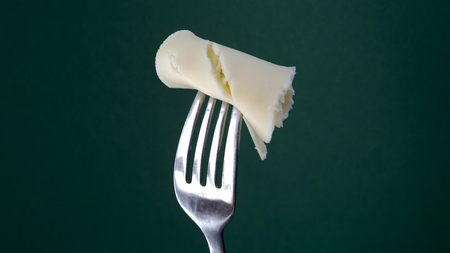 fork with slice of cheese on a green backgroundの写真素材