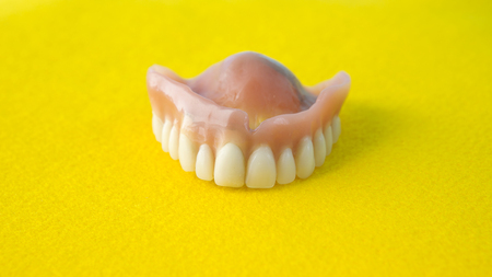 closeup of teeth denture on a yellow table